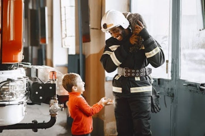 Firefighter teaching a young child about fire safety in a friendly, reassuring way
