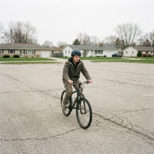 A teenage rider practising alone in a wide empty parking lot with no cars in it.