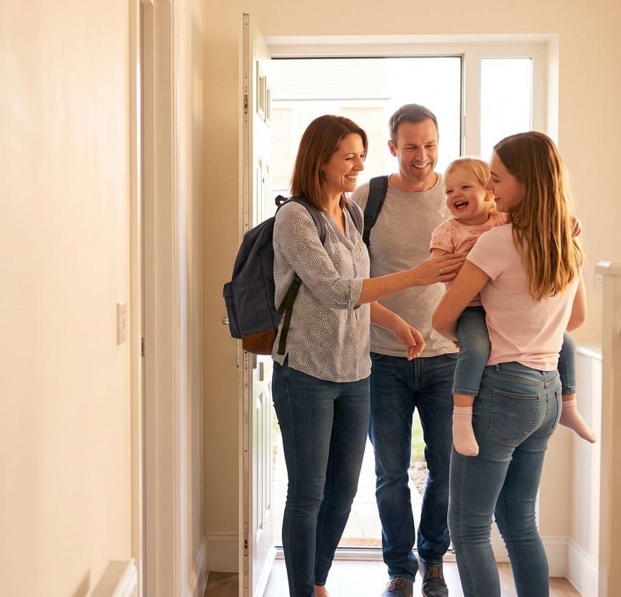 A teenager handing a toddler back to her parents at the front door